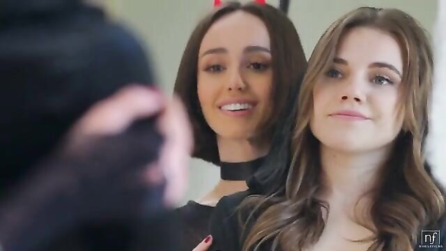 Two sexy brunettes in sheer black tops smile playfully for Halloween slut scene