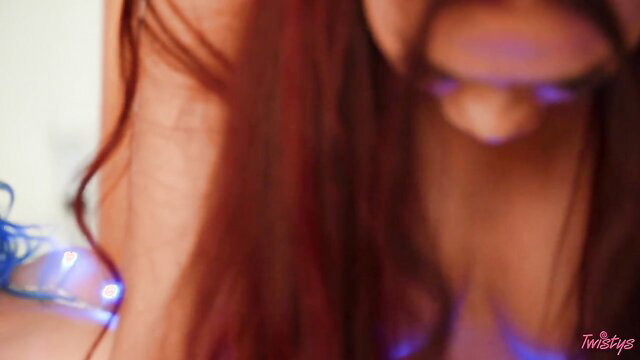 Sabina Rouge's red-haired cleavage shine in festive fetish glow