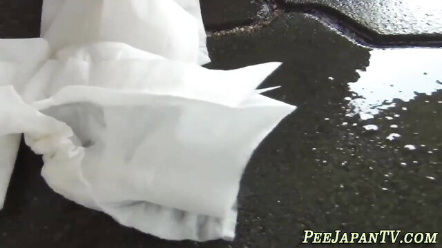 Asian teen wiping pussy after peeing on wet pavement