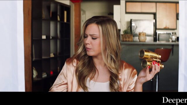 Avery Cristy holding gold binoculars in pink satin robe