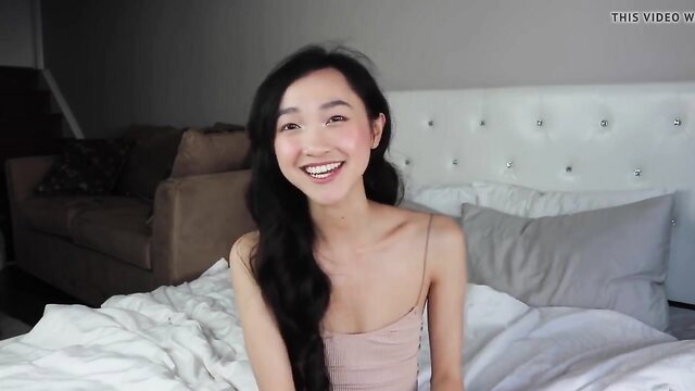 Clara Dao stunning Asian YouTuber smiling in pink tank top on bed