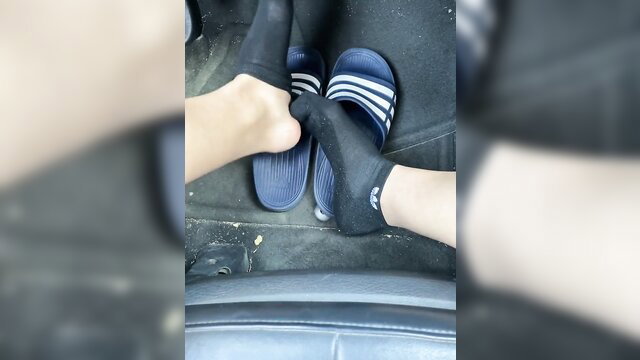 Car seat foot fetish closeup: pale legs in black ankle socks and Adidias slides