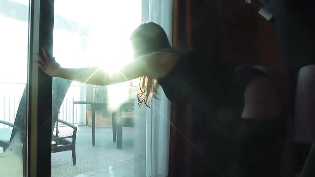 Amateur brunette leaning out balcony door in tight dress on vacation