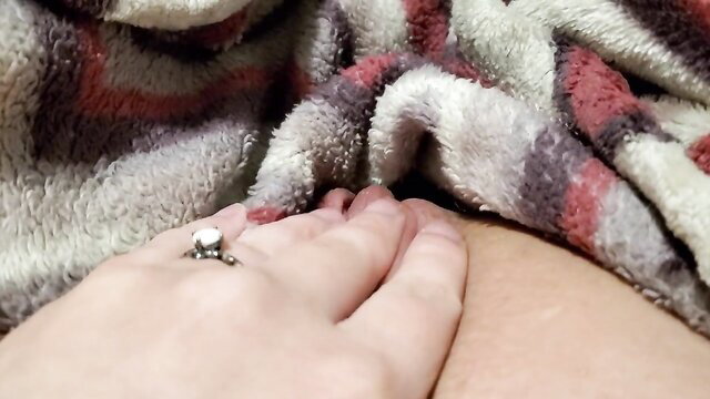 Amateur solo woman jilling pussy with left hand under blanket closeup