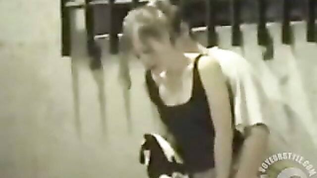 Blonde woman in tank top bending over in public alley tease