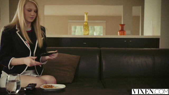 Blonde Lily Rader in schoolgirl skirt on couch with pasta
