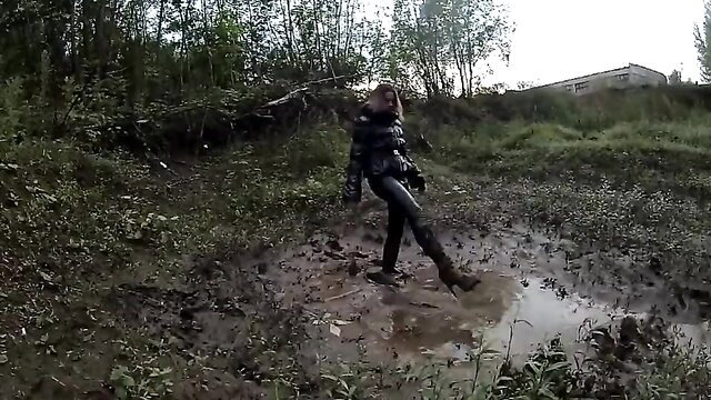 Hot brunette in latex catsuit wading through muddy forest adventure