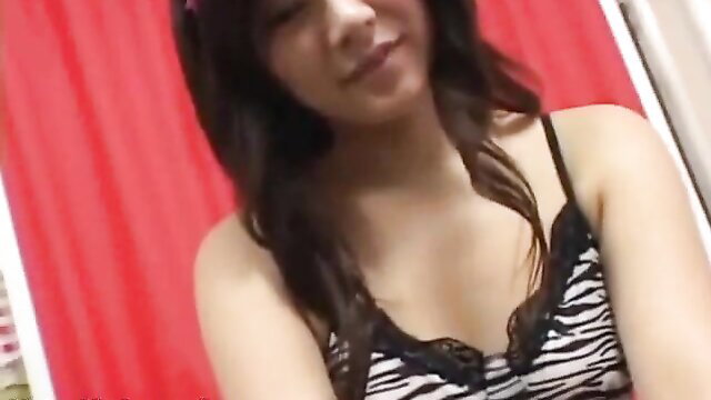 Asian beauty in zebra lingerie smiles seductively in bedroom