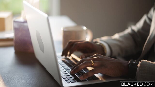 Hazel Moore typing on laptop in office suit, elegant hands closeup