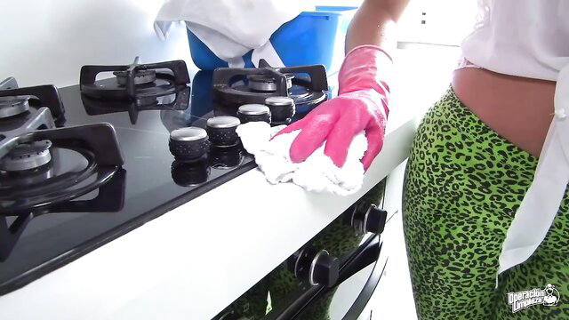 Hot model in green leopard pants and pink gloves cleans stove
