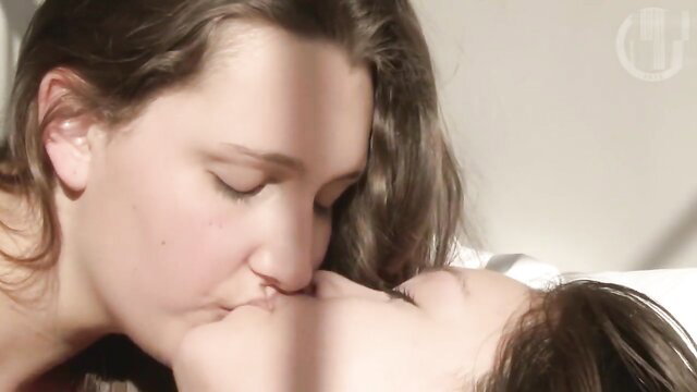 Two pretty brunettes passionately French kissing in bed