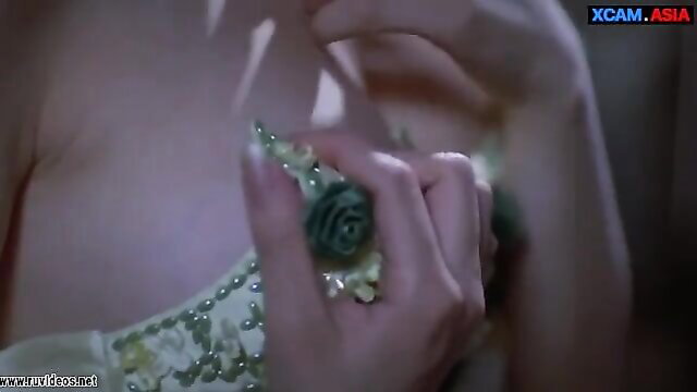 Asian woman in green beaded dress holding rose flower on cleavage