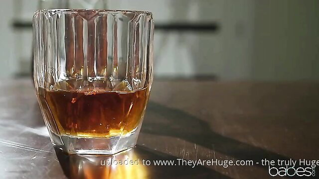 Closeup of whiskey glass on table in dimly lit room