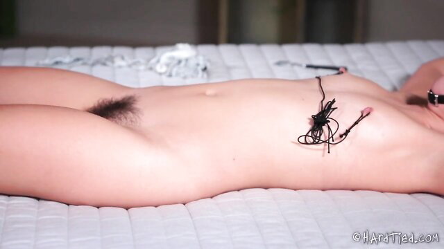 Bound nude Asian beauty with hairy pussy, tied nipples on bed