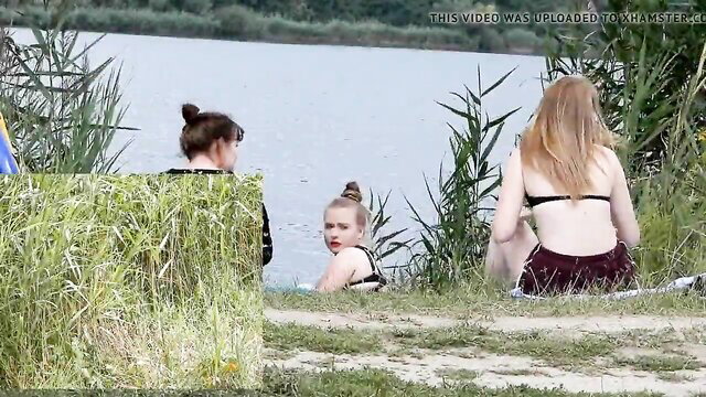 Three bikini girls watch naked guy swimming nude at lake