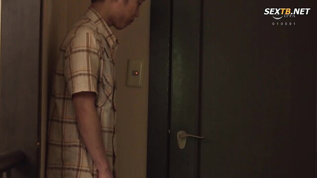 Asian man in checkered shirt stands by door in JAV prank setup