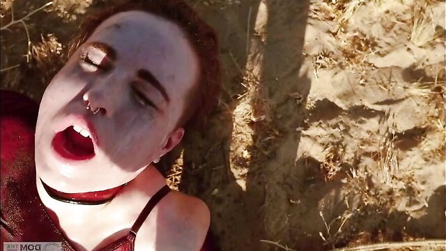 Pale goth girl with red hair screaming mouth open in red lingerie outdoors