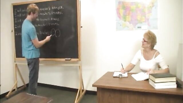Blonde older teacher teases student with reach around in classroom