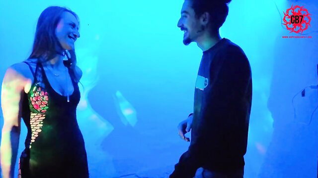 Hot redhead in sexy black dress flirts with handsome guy at neon club