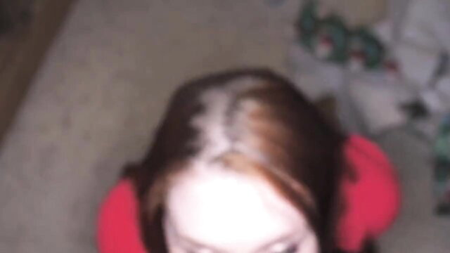 Teen redhead in red earmuffs under Christmas tree, pale skin big tits