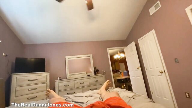 Danni Jones feet up on bed in orange shorts panty try on tease