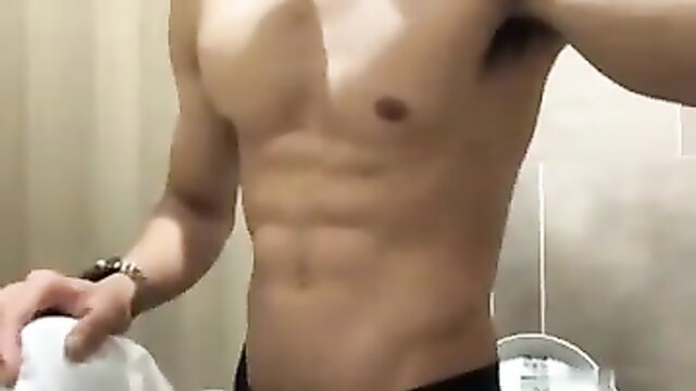Fit Asian guy with ripped abs posing shirtless in bathroom