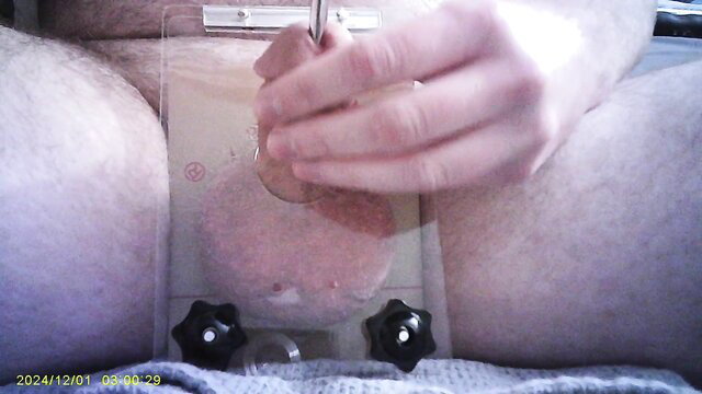 Man crushing small penis with clamp while sounding rod inserted