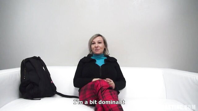 Blonde mature amateur mommy in turtleneck and pants sits smiling