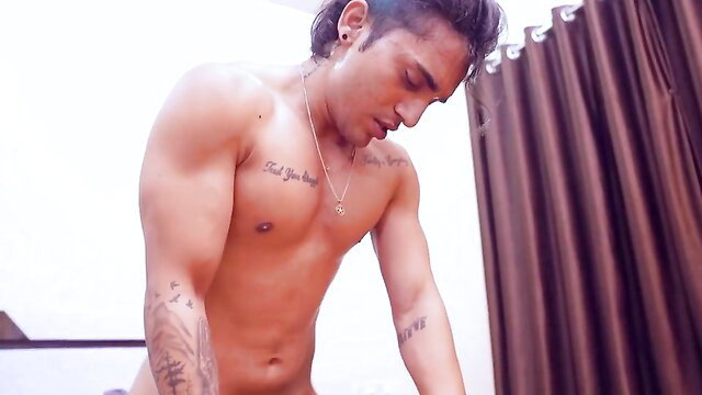 Shirtless muscular Indian man with tattoos flexing abs
