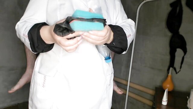 Woman in lab coat holds black and teal sponges for DIY male masturbator
