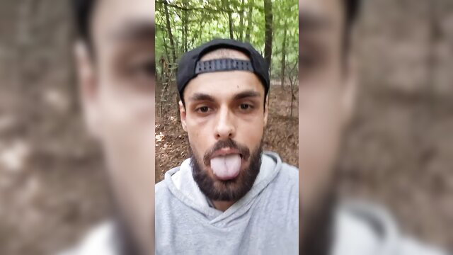Bearded man in cap and hoodie ambling alone in forest, insatiable vibe