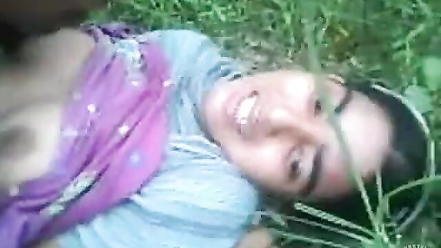 Smiling Indian girl in saree lying on grass, outdoor tease