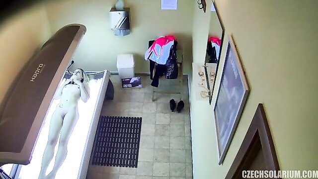 Blonde babe nude tanning in solarium bed, full body view