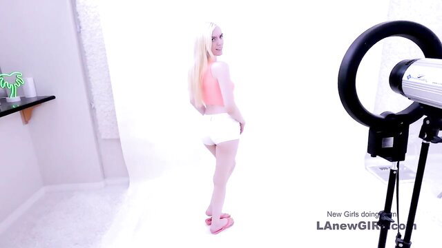 Cute blonde babe in tiny white shorts poses sexy in studio