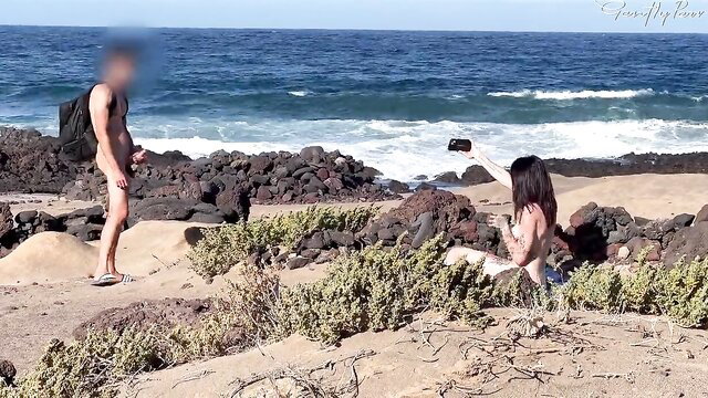 Nude couple on beach: man shows hard cock, woman kneels for blowjob