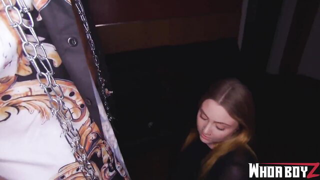 Sybil A in chains and leather top, seductive pose in dark room