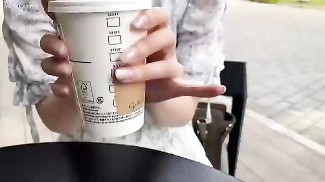Asian beauty in sheer dress holds Starbucks cup, teasing fingers out