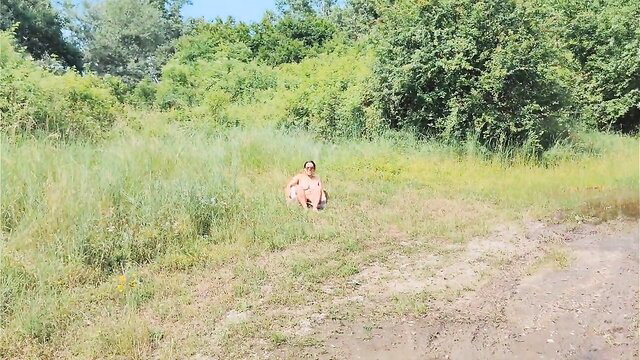 Nude woman sitting in lush green field, outdoor nature fantasy