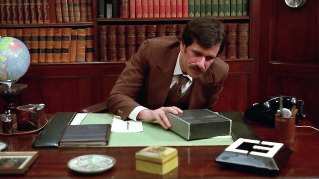 Man in suit examines metal box in vintage 1980 porn Justine: A Matter of Innocence