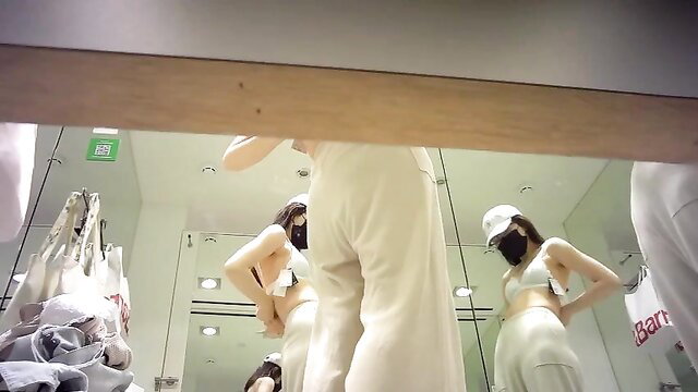 Asian beauty trying on skimpy white lingerie in store mirror