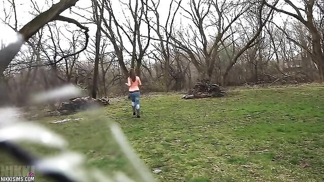 Brunette woman running in woods wearing pink top and jeans