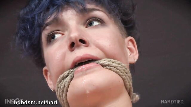 Blue-haired beauty bound in rope, gagged, eyes wide in ecstasy