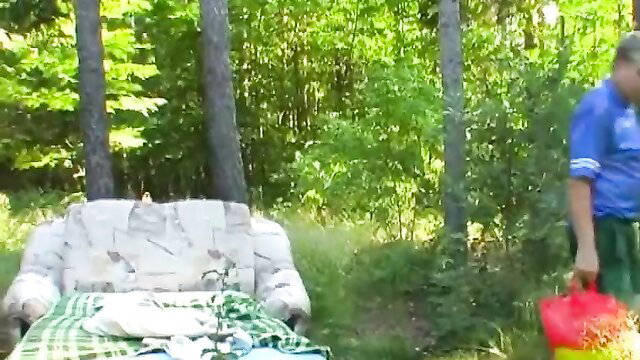Slim teen on checkered blanket in forest with man holding bucket