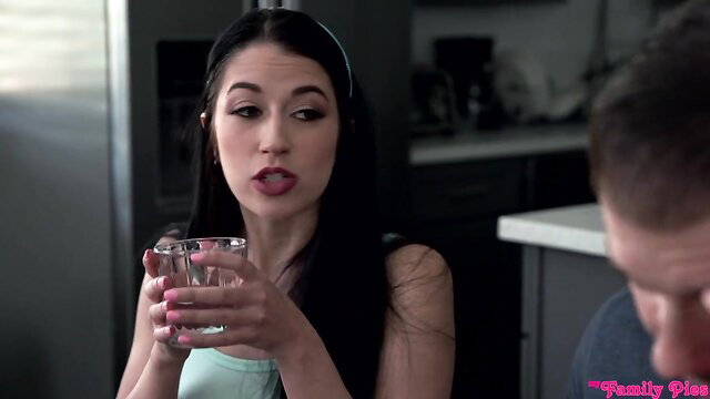 Brunette mom in tank top holds glass, teases in kitchen prank scene