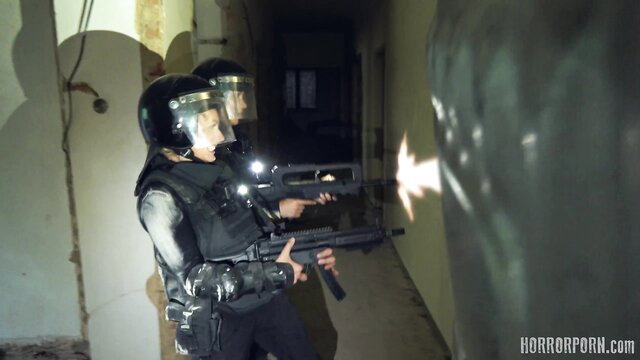 Two hot riot police women with guns in dark zombie strike scene
