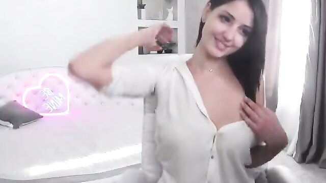 Brunette camgirl flexing arm in open white blouse showing huge cleavage