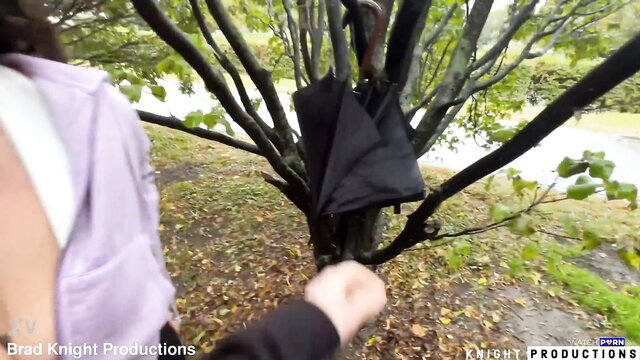 Betty Buttplug in purple top outdoors by tree with black bag, cumwalk tease