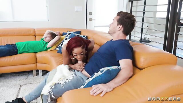 Redhead ebony babe deepthroats on couch with man watching