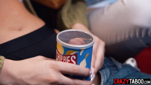 Woman holding Pringles can with dick visible on lid, topless tease