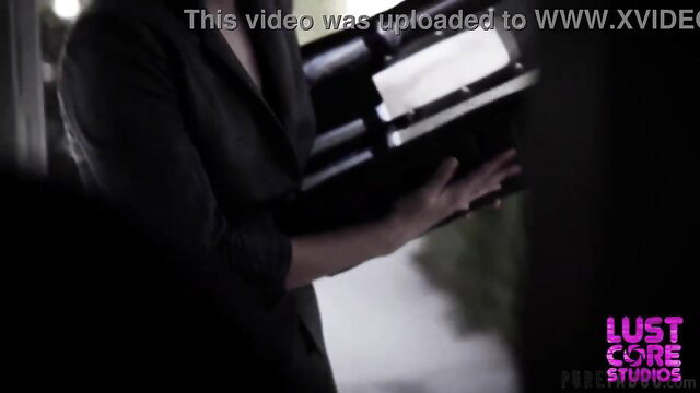 Mystery woman in black blazer holds object in dark Lust Studios scene